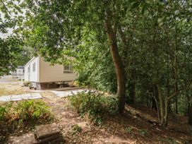 A mobile home surrounded by trees and shrubs at Plot 13A
