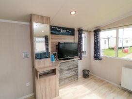 A living room with a television and a mirror at 42 Oak Green
