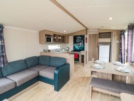 A living room with a couch and kitchen area at 42 Oak Green