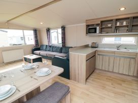 A living room with a kitchen area and dining table at 42 Oak Green 