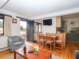 A living room with a dining area and television at Iris at Stancombe Manor Sherford near Chillington