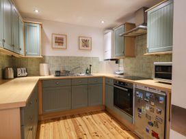 A kitchen with cabinets and appliances at Iris at Stancombe Manor Sherford near Chillington
