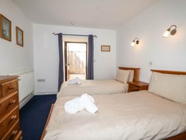 A bedroom with two beds and a door opening to an outdoor area at Iris at Stancombe Manor Sherford near Chillington