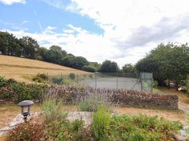 An outdoor area featuring a tennis court and flower bed at Iris at Stancombe Manor Sherford near Chillington
