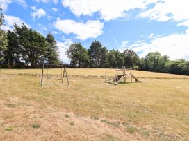 A swing set and play structure in an outdoor area at Iris at Stancombe Manor Sherford near Chillington
