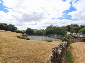 A tennis court surrounded by grass and trees at Iris at Stancombe Manor Sherford near Chillington