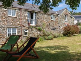 An outdoor area with a stone building and deck chairs at The Granary