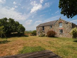 A house with windows and a door surrounded by grass and trees at The Granary