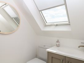 A bathroom featuring a toilet, sink, and a round mirror at Tower View Cottage in Lympstone