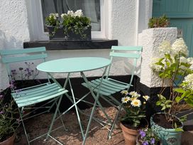 A table and chairs with flower pots in an outdoor area at Tower View Cottage Lympstone