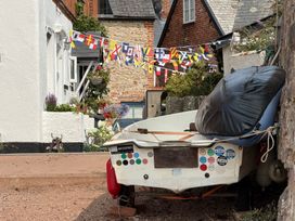A boat parked beside a building with flags and flowers at Tower View Cottage in Lympstone