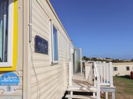 A caravan exterior with a deck and sign at Beech Walk 3 Sandy Bay Exmouth