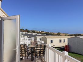 An outdoor area with chairs and a table overlooking caravans at Beech Walk 3 in Sandy Bay, Exmouth