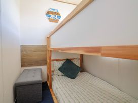 A bedroom with a bunk bed and an ottoman at Beech Walk 3 in Sandy Bay, Exmouth