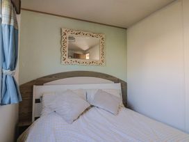 A bedroom with a bed and mirror at Beech Walk 3 in Sandy Bay, Exmouth