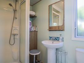 A bathroom with a shower, sink, and mirror at Beech Walk 3 Sandy Bay, Exmouth