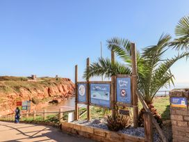 An outdoor sign and palm tree along a coastal path at Beech Walk 3 Sandy Bay, Exmouth