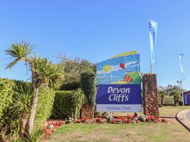 A sign for Devon Cliffs Holiday Park with flags and palm trees at Beech Walk 3, Sandy Bay, Exmouth