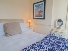 A bedroom with a bed, nightstand, lamp, and framed picture at 2 St. Michaels House in Lyme Regis