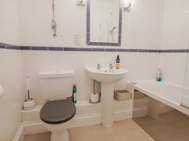 A bathroom with a toilet, sink, mirror, and bathtub at 2 St. Michaels House Lyme Regis