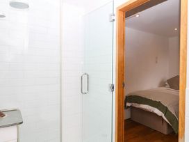A bathroom with a shower and a bedroom visible at The Hayloft at Manaton