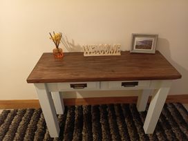 An entryway table with a welcome sign and decorative items at Sliabh League Mountain Lodge in TEILEANN near Kilcar, County Donegal