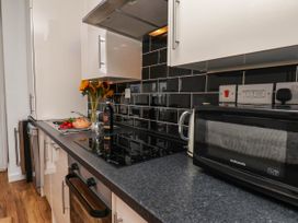 A kitchen with a stove, microwave, sink, and various items at Flat 1 in Whitby