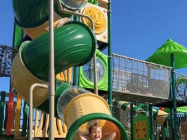A playground with slides and a child on equipment at Sandy beach retreat in Prestatyn