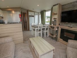 A living room with kitchen area and dining table at 101 Bay View in Ayr