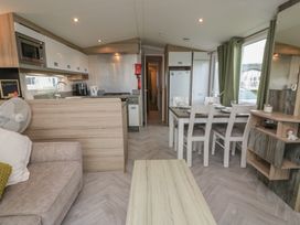 A living room with a sofa and dining area at 101 Bay View in Ayr