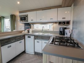 A kitchen with a sink, microwave, and gas stove at 101 Bay View, Ayr