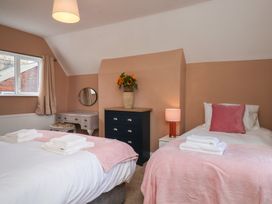 A bedroom with two beds, a dresser, and a mirror at Lansdowne Grange in Bridlington