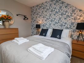 A bedroom with a bed, dresser, and floral wallpaper at Lansdowne Grange in Bridlington
