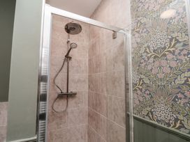 A shower with a shower head and tiled walls at Lansdowne Grange in Bridlington
