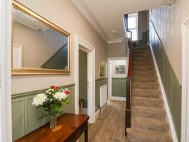 A hallway with a staircase and a mirror at Lansdowne Grange in Bridlington