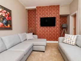 A living room with a grey sofa and television at Lansdowne Grange in Bridlington