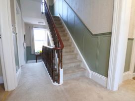 A hallway with a staircase and window at Lansdowne Grange in Bridlington