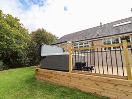 An outdoor area with a hot tub and deck at Hedley Dene Cottage in Longhorsley