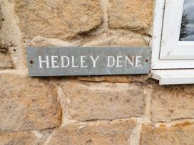 A sign displaying 'HEDLEY DENE' attached to a stone wall at Hedley Dene Cottage in Longhorsley