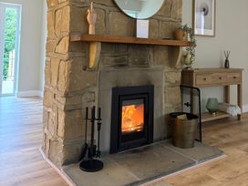 A living room with a stone fireplace and side table at Hedley Dene Cottage Longhorsley