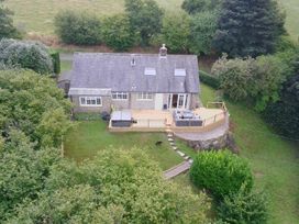 A cottage with a deck and hot tub in the garden at Hedley Dene Cottage in Longhorsley