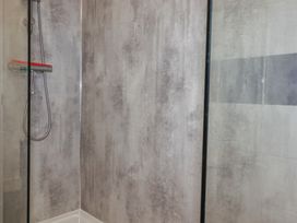 A shower area with a glass door and a showerhead at Newseal House