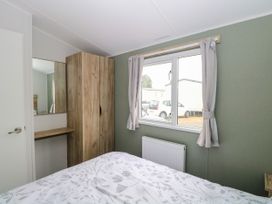 A bedroom with a bed, wardrobe and mirror at Haven Seashore, Ellerton Willerby Xtra in Great Yarmouth
