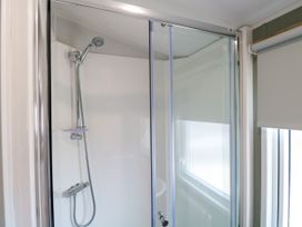 A shower with a glass door and faucet at Haven Seashore, Ellerton Willerby Xtra, Great Yarmouth