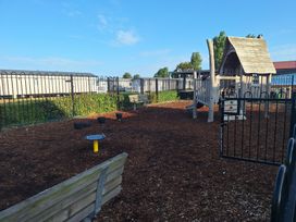 A playground with a wooden play structure and benches at Haven Seashore, Ellerton Willerby Xtra, Great Yarmouth