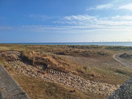 A landscape showing sand, grass, sea, and wind turbines at Haven Seashore, Ellerton Willerby Xtra, Great Yarmouth