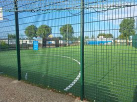 A sports field with a fence and artificial turf at Haven Seashore, Great Yarmouth