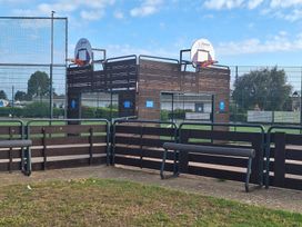 An outdoor basketball court with hoops and benches at Haven Seashore, Great Yarmouth