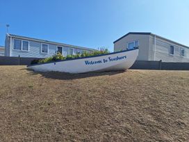 A boat in a garden with a house in the background at Haven Seashore, Great Yarmouth