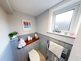 A bathroom with a toilet and shelf holding towels at 44 Norwood Street, Scarborough